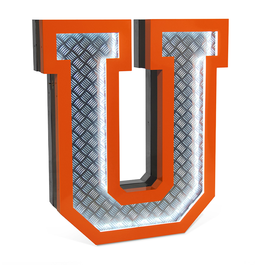 Inspired by the great 70's, the geometric lines and the exterior orange underlines that contour the Aluminium fixture is a sign of the times ahead. Covered with diamond plated steel that reflects the white neon glow of the marquee lighting design is the ones to characterizes this lighting fixture. Creating a new aura in any design project, this handmade lighting design has a 1 meter in height.